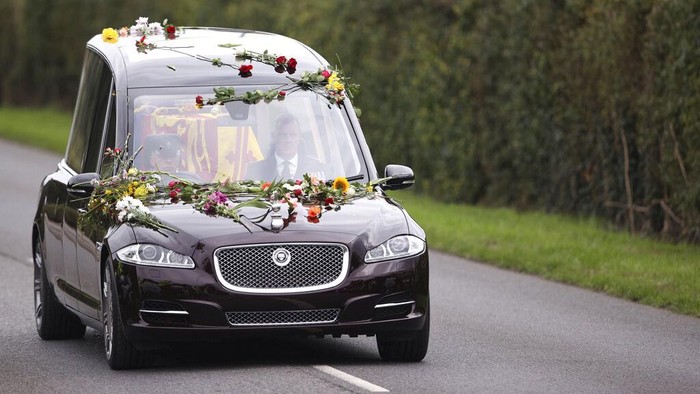 Mobil Inggris Ini Antar Ratu Elizabeth II ke Peristirahatan Terakhir Flowers cover the hearse carrying the coffin of Queen Elizabeth II as it arrives on the Albert Road outside Windsor Castle in Windsor, England, Monday, Sept. 19, 2022. The Queen, who died aged 96 on Sept. 8, will be buried at Windsor alongside her late husband, Prince Philip, who died last year. (Molly Darlington/Pool Photo via AP)