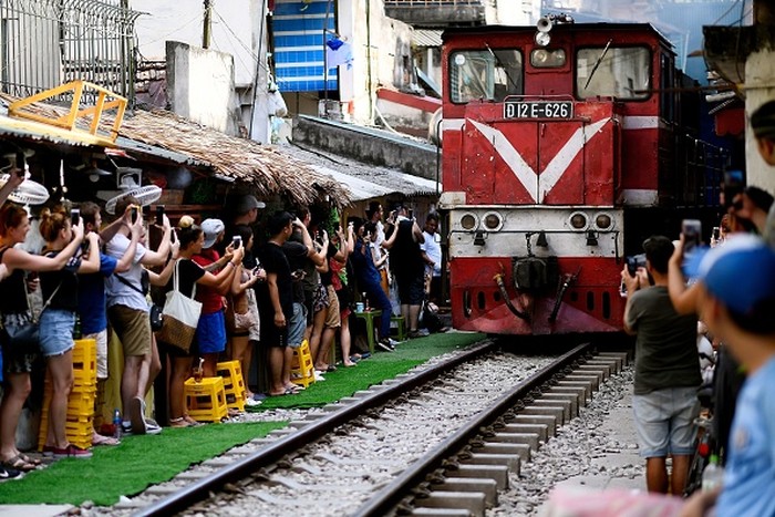 This photograph taken on June 9, 2019 shows a family posing for a selfie on the railway track in Hanois popular train street. (Photo by Manan VATSYAYANA / AFP)        (Photo credit should read MANAN VATSYAYANA/AFP via Getty Images)