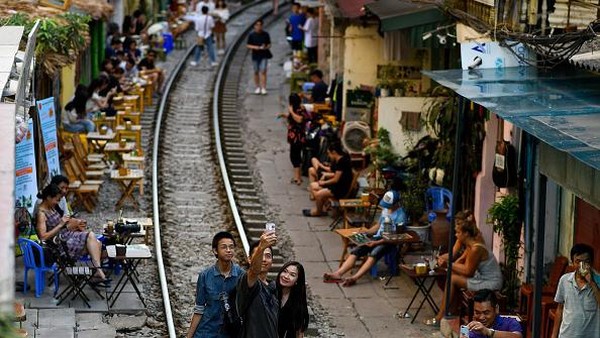 Deretan kafe itu ada di samping kereta berjalan di sepanjang jalur yang hanya beberapa inci dari rumah dan bisnis di ibu kota Vietnam. Lokasi itu telah lama menjadi salah satu lokasi wisata favorit di media sosial. (Manan Vatsyayana/AFP/Getty Images)  