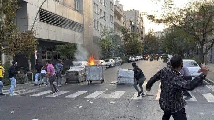 In this Tuesday, Sept. 20, 2022, photo taken by an individual not employed by the Associated Press and obtained by the AP outside Iran, protesters throw stones at anti-riot police during a protest over the death of a young woman who had been detained for violating the countrys conservative dress code, in downtown Tehran, Iran. Iran faced international criticism on Tuesday over the death of a woman held by its morality police, which ignited three days of protests, including clashes with security forces in the capital and other unrest that claimed at least three lives. (AP Photo)