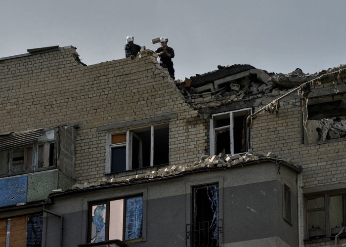 1243417346 KHARKIV, UKRAINE - 2022/09/21: People look at a partially destroyed residential building that was damaged as a result of a missile attack by the Russian army. Russia invaded Ukraine on 24 February 2022, triggering the largest military attack in Europe since World War II. (Photo by Sergei Chuzavkov/SOPA Images/LightRocket via Getty Images)