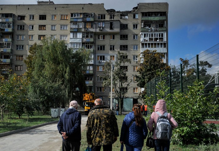 KHARKIV, UKRAINE - 2022/09/21: People look at a partially destroyed residential building that was damaged as a result of a missile attack by the Russian army. Russia invaded Ukraine on 24 February 2022, triggering the largest military attack in Europe since World War II. (Photo by Sergei Chuzavkov/SOPA Images/LightRocket via Getty Images)