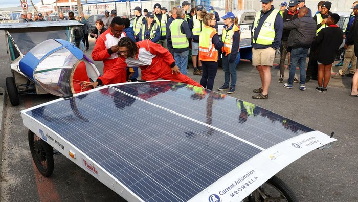 Ketika Mobil Tenaga Matahari Adu Gengsi di Afrika Selatan School learners look at the Netherlands's Brunel Solar Team car as it participates on the final stage of the 2022 Sasol Solar Challenge Race, near Cape Town, South Africa, September 16, 2022. REUTERS/Esa Alexander
