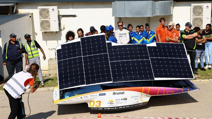 Ketika Mobil Tenaga Matahari Adu Gengsi di Afrika Selatan School learners look at the Netherlands's Brunel Solar Team car as it participates on the final stage of the 2022 Sasol Solar Challenge Race, near Cape Town, South Africa, September 16, 2022. REUTERS/Esa Alexander