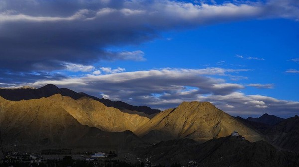 Cahaya matahari terbenam yang jatuh di pegunungan. Terlihat awan menutupi sebagian langit biru di wilayah gurun yang dingin di Ladakh, India, Selasa (20/9/2022).