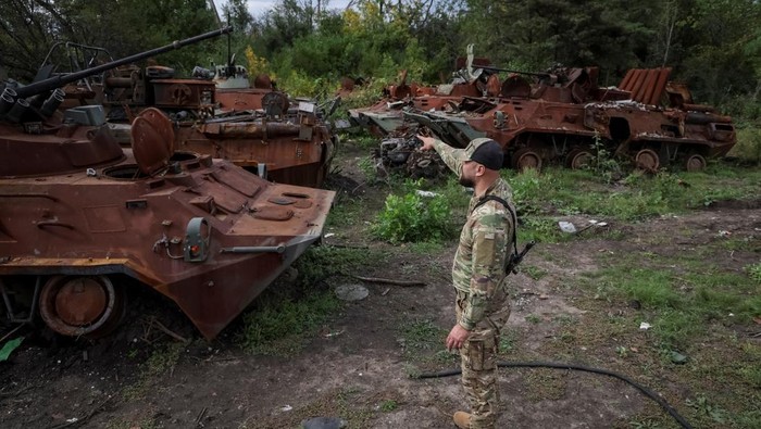Penampakan Kuburan Kendaraan Tempur Rusia di Izium, Ukraina Ukrainian serviceman checks a destroyed Russian Armoured Personnel Carrier (APC), as Russia's attack on Ukraine continues, in the town of Izium, recently liberated by Ukrainian Armed Forces, in Kharkiv region, Ukraine September 20, 2022. REUTERS/Gleb Garanich TPX IMAGES OF THE DAY