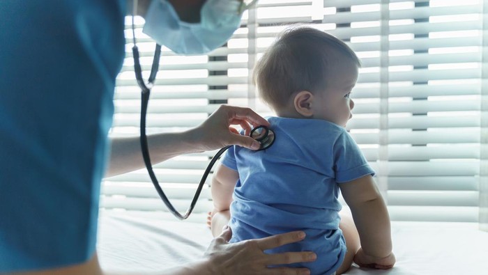 Asian female Pediatrician doctor examining her little baby patient with stethoscope in medical room at hospital.