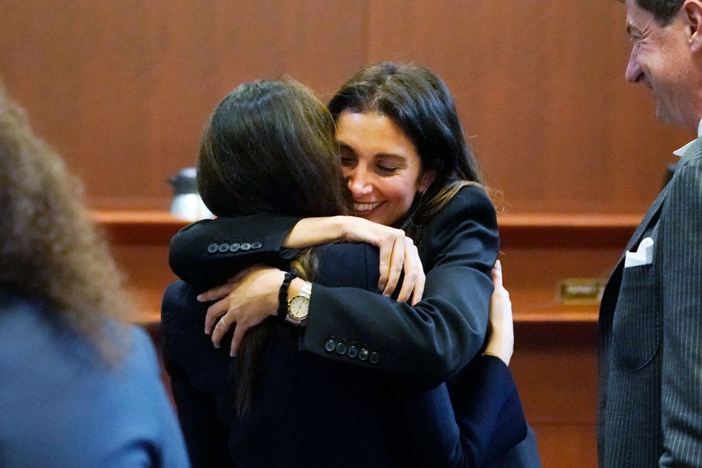 Attorney Joelle Rich hugs attorney Camille Vasquez, back to camera, as attorney Ben Chew (R) looks on, at the end of the daily proceedings at the Fairfax County Circuit Courthouse in Fairfax, Virginia, May 16, 2022. - US actor Johnny Depp sued his ex-wife Amber Heard for libel in Fairfax County Circuit Court after she wrote an op-ed piece in The Washington Post in 2018 referring to herself as a 