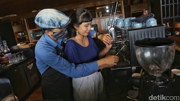 Rindia membantu peserta untuk mengekstrasi bubuk kopi di mesin kopi espresso.