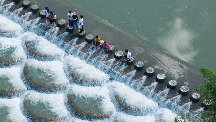 XIANFENG, CHINA - JULY 28: Tourists cool off at a location known for fish scale-shaped barriers that form small waterfalls during a hot summer day on July 28, 2022 in Xianfeng County, Enshi Tujia and Miao Autonomous Prefecture, Hubei Province of China. (Photo by Ye Xingjian/VCG via Getty Images)