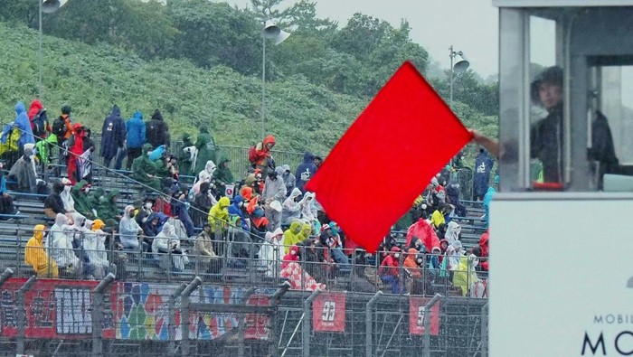 Spectators sit in the stands as a marshal displays the red flag due to bad weather during the Moto2 practice session of the Japanese Grand Prix at the Mobility Resort Motegi in Motegi, Tochigi prefecture on September 24, 2022. (Photo by Toshifumi KITAMURA / AFP) (Photo by TOSHIFUMI KITAMURA/AFP via Getty Images)