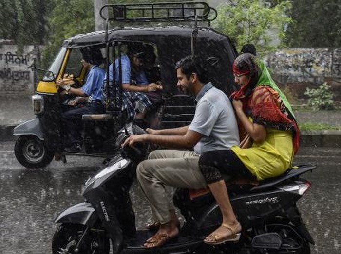 Commuters make their way along a road during a heavy rainfall in Amritsar on September 23, 2022. (Photo by Narinder NANU / AFP)