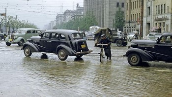 Foto berwarna di tahun 1950-an membawa nostalgia kota Tokyo di masa itu. Ini suasana jalan di salah satu sudut kota yang tergenang karena hujan. Foto: Vintag.es