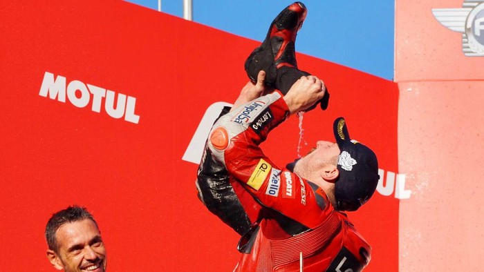 MotoGP Japanese Grand Prix winner Ducati Lenovo team rider Jack Miller of Australia (R) drinks champagne from his boot as he celebrates on the podium after winning the MotoGP class race at the Japanese Grand Prix in Motegi, Tochigi prefecture on September 25, 2022. (Photo by Toshifumi KITAMURA / AFP) (Photo by TOSHIFUMI KITAMURA/AFP via Getty Images)