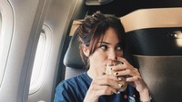 Kali ini Enzy Storia sedang asik minum segelas kopi di pesawat. Kira-kira Enzy mau kemana ya?  Foto: Instagram @enzystoria