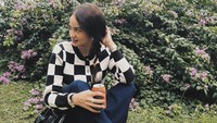 Sambil duduk-duduk di taman, Enzy Storia bersantai ria minum minuman kaleng. Foto: Instagram @enzystoria