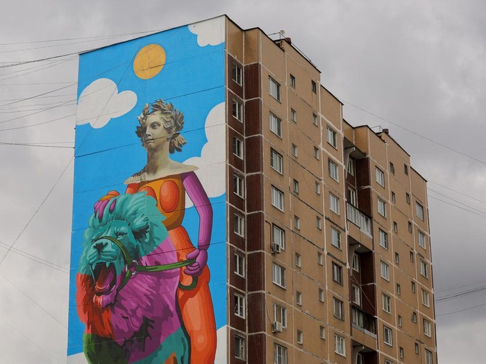 A woman walks along the street with the murals on display on multi-storey apartment blocks seen in the background during the international festival Urban Morphogenesis, held in the town of Balashikha outside Moscow, Russia, September 20, 2022. REUTERS/Evgenia Novozhenina