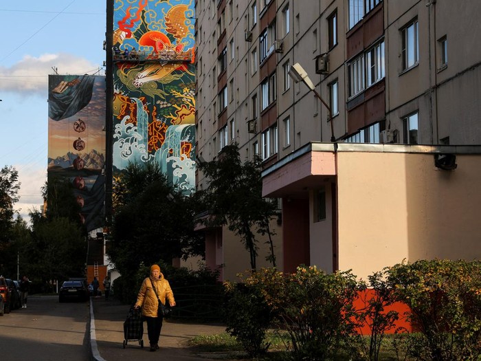 A woman walks along the street with the murals on display on multi-storey apartment blocks seen in the background during the international festival Urban Morphogenesis, held in the town of Balashikha outside Moscow, Russia, September 20, 2022. REUTERS/Evgenia Novozhenina