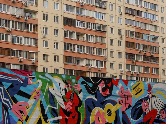 Penampakan Mural di Gedung-gedung Bertingkat Moskow, Keren Banget A woman walks along the street with the murals on display on multi-storey apartment blocks seen in the background during the international festival Urban Morphogenesis, held in the town of Balashikha outside Moscow, Russia, September 20, 2022. REUTERS/Evgenia Novozhenina