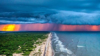 Pemandangan menakjubkan di pantai Carolina Utara saat badai berpadu dengan matahari terbenam.  