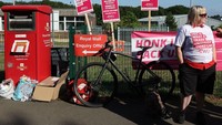 Akibatnya buruh berbagai profesi di seluruh Inggris melakukan aksi protes menuntut naik gaji. Salah satunya pekerja pos dari Royal Mail yang berdemo di depan kantor pengiriman pos Basingstoke pada Agustus lalu. Foto: AFP via Getty Images/ADRIAN DENNIS