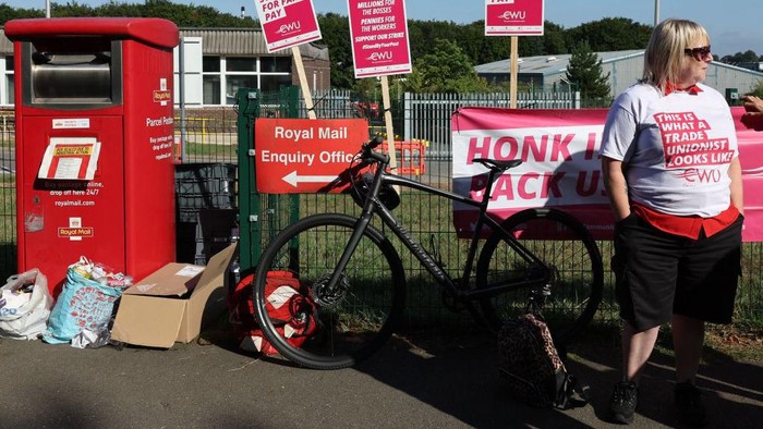 TOPSHOT - A Royal Mail postal worker stands at a picket line outside the Basingstoke delivery office on August 26, 2022 during a strike over pay. - The Royal Mail Basingstoke delivery office had a 100 percent turnout for the nationwide strike with each of its 220 workers, all members of the Communication Workers Union (CWU), taking part. (Photo by Adrian DENNIS / AFP) (Photo by ADRIAN DENNIS/AFP via Getty Images)