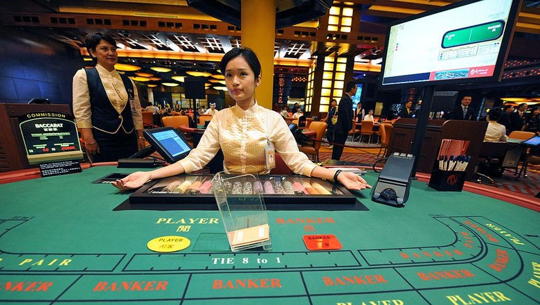 A dealer stands by a table at the opening of Singapores first casino, the Resorts World Sentosa complex, in Singapore on February 14, 2010. Singapores first casino opened for business when the first punter was allowed into the gaming section of Resorts World Sentosa complex. The opening -- to be followed within months by a second casino resort -- is part of a multi-billion-dollar effort to transform Singapores tourism industry. AFP PHOTO/ROSLAN RAHMAN (Photo credit should read ROSLAN RAHMAN/AFP via Getty Images)