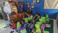 Petugas memberikan edukasi mengenai informasi seputar pemadam kebakaran. Anak-anak TK memperhatikan apa yang disampaikan oleh para petugas yang sedang menjelaskan.
