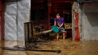 Warga membuang air banjir yang masuk ke dalam rumah. Banjir mulai meluas di beberapa daerah di Filipina.