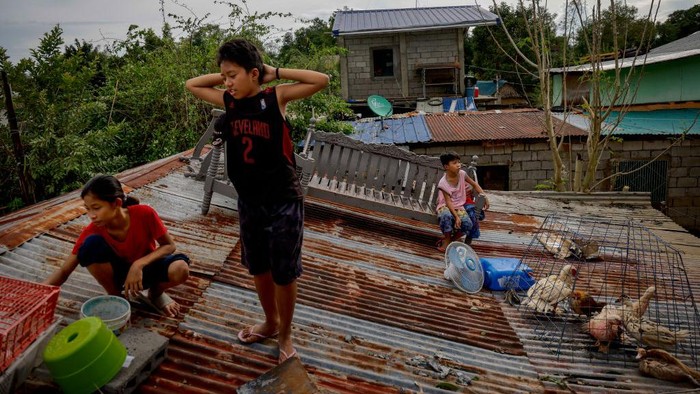 SAN MIGUEL, PHILIPPINES - SEPTEMBER 26: Children remain stranded in the rooftop of their home after Super Typhoon Noru submerged their village in floodwaters on September 26, 2022 in San Miguel, Bulacan province, Philippines. Super Typhoon Noru made landfall in the Philippines overnight, causing widespread flooding and leaving at least five dead. High winds and heavy rains have flattened villages and have increased the threat of landslides. (Photo by Ezra Acayan/Getty Images)