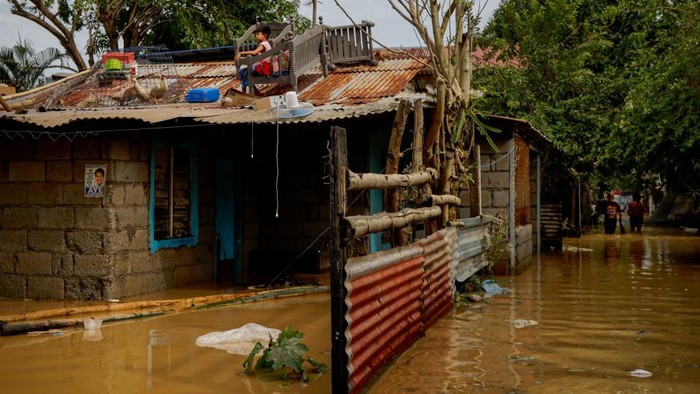 Banjir Hantam Filipina, Rumah Terendam-5 Orang Tewas SAN MIGUEL, PHILIPPINES - SEPTEMBER 26: Children remain stranded in the rooftop of their home after Super Typhoon Noru submerged their village in floodwaters on September 26, 2022 in San Miguel, Bulacan province, Philippines. Super Typhoon Noru made landfall in the Philippines overnight, causing widespread flooding and leaving at least five dead. High winds and heavy rains have flattened villages and have increased the threat of landslides. (Photo by Ezra Acayan/Getty Images)