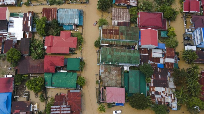 In this image taken with a drone, vehicles pass by a flooded road due to Typhoon Noru in San Miguel town, Bulacan province, Philippines, Monday, Sept. 26, 2022. Typhoon Noru blew out of the northern Philippines on Monday, leaving some people dead, causing floods and power outages and forcing officials to suspend classes and government work in the capital and outlying provinces. (AP Photo/Aaron Favila)