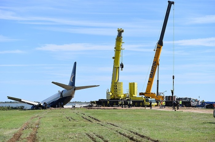This photograph from September 25, 2022, shows cranes next to an Aeropostale Boeing 737 cargo plane after it overrun the runway during its night landing phase at Montpellier airport. - French authorities on September 24 closed the airport in the southern city of Montpellier for an indefinite period after a cargo plane overran the runway and ended up with its nose in a nearby lake. (Photo by Sylvain THOMAS / AFP) (Photo by SYLVAIN THOMAS/AFP via Getty Images)