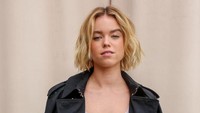 Milly Alcock tampil dengan dress dominan putih yang awalnya dibalut coat hitam. (Foto: Dave Benett/Getty Images for Burberry) 