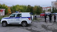 Seorang wanita berbicara kepada petugas polisi yang mengamankan area setelah penembakan di sekolah di Izhevsk, Rusia, Senin, (26/9/2022). (REUTERS/Stringer)