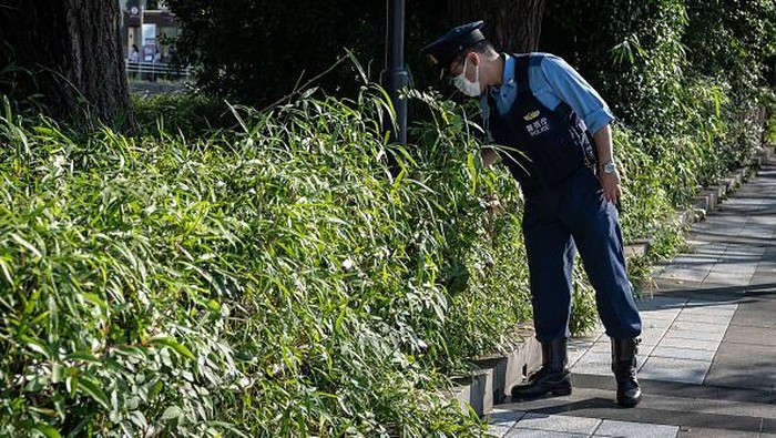 Jelang Pemakaman Shinzo Abe, Jepang Terapkan Pengamanan Super Ketat A police officer inspects a bush near the Nippon Budokan ahead of the state funeral for former Japanese prime minister Shinzo Abe in Tokyo on September 27, 2022. - Thousands of Japanese and foreign dignitaries have gathered in Tokyo on September 27 to honour Abe, at a rare state funeral that has sparked controversy and protest.