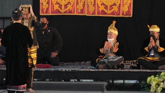 Presiden Joko Widodo (kedua kiri) mengenakan mahkota Kesultanan Buton serta pakaian adat saat prosesi penganugerahan gelar kehormatan di Keraton Buton, Baubau, Sulawesi Tenggara, Selasa (27/9/2022). Presiden dalam kunjungan kerjanya di Kepulauan Buton Sulawesi Tenggara dianugerahi gelar adat dan budaya bergelar La Ode Joko Widodo Lakina Bhawaangi Yi Nusantara dari Sultan Buton ke-40 sekaligus dinyatakan menjadi warga, kerabat serta sesepuh Kesultanan Buton. ANTARA FOTO/Jojon/rwa.