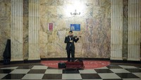 Ini adalah Stasiun Teatralnaya. Seorang musisi berpakaian jas, memainkan biola. Agar bisa menggelar pertunjukan di dalam stasiun, ia terlebih dulu harus lolos seleksi dari pihak berwenang.