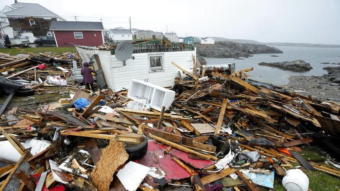 A resident and search and rescue worker examine the destroyed remains of a home in Port aux Basques, Newfoundland and Labrador, Monday, Sept. 26, 2022. Across the Maritimes, eastern Quebec and in southwestern Newfoundland, the economic impact of hurricane Fiona's wrath is still being tallied. (Frank Gunn/The Canadian Press via AP)