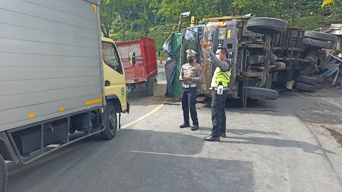 Petugas melakukan pengaturan lalu lintas di lokasi truk terguling.