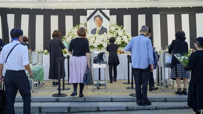 Warga Jepang Beri Penghormatan Terakhir Jelang Pemakaman Shinzo Abe People leave flowers and pay their respects to former Japanese Prime Minister Shinzo Abe outside the Nippon Budokan in Tokyo Tuesday, Sept. 27, 2022, ahead of his state funeral later in the day. (Kyodo News via AP)