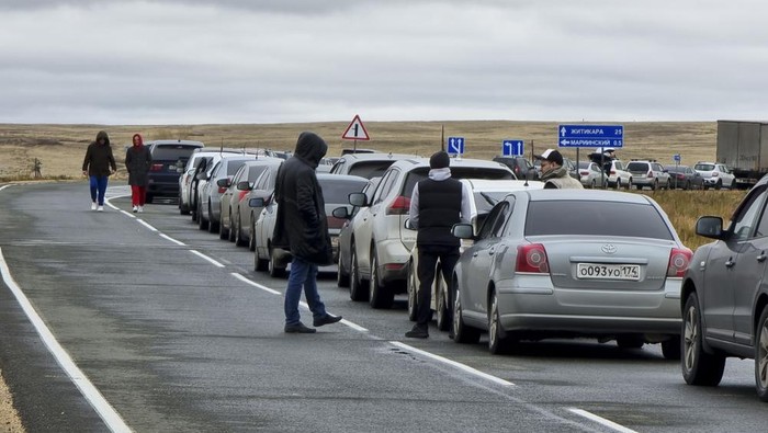 People walk next to their cars queuing to cross the border into Kazakhstan at the Mariinsky border crossing, about 400 kilometers (250 miles) south of Chelyabinsk, Russia, Tuesday, Sept. 27, 2022. Officials say about 98,000 Russians have crossed into Kazakhstan in the week since President Vladimir Putin announced a partial mobilization of reservists to fight in Ukraine. (AP Photo)