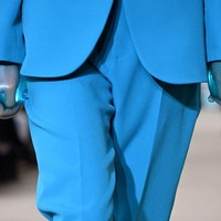Air merupakan elemen utama yang jadi inspirasi busana berpotongan tailoring ini. Salah satunya ditampilkan oleh model yang mengenakan setelan celana panjang dan blazer dengan kedua tangan terbungkus sarung tangan bernuansa aquatik. Foto: Getty Images