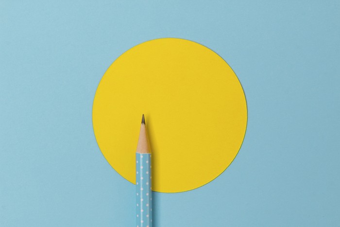 Top view of turquoise polka dot pencil on colorful paper combine with yellow circle. Minimalist template with copy space.