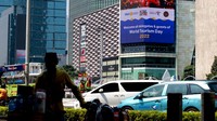 Warga melintas di dekat layar yang menampilkan iklan tiket.com di Jakarta, Selasa (27/9/2022).