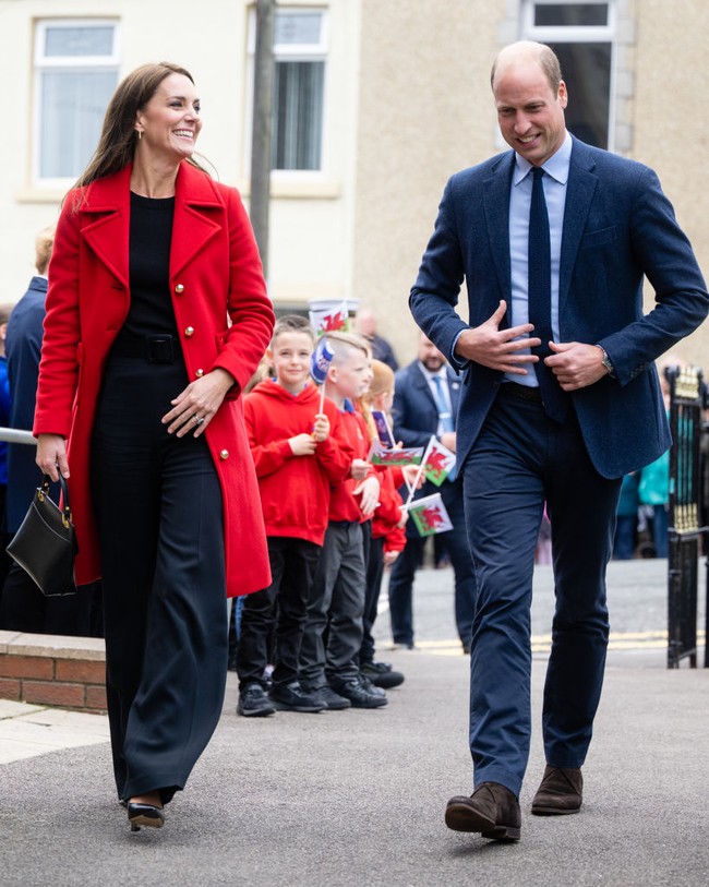 Kate Middleton tampil simple untuk kunjungannya ke Wales. Dia memadukan coat merahnya dengan celana panjang high waist dan atasan hitam.  Foto: Getty Images