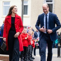 Kate Middleton tampil simple untuk kunjungannya ke Wales. Dia memadukan coat merahnya dengan celana panjang high waist dan atasan hitam.  Foto: Getty Images