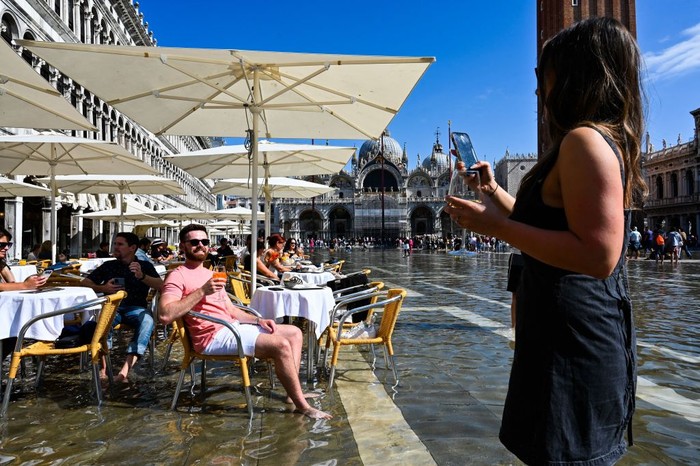 TOPSHOT - Tourists walk across elevated walkways outside St. Marks Basilica on St. Marks square in Venice on September 27, 2022, following an 
