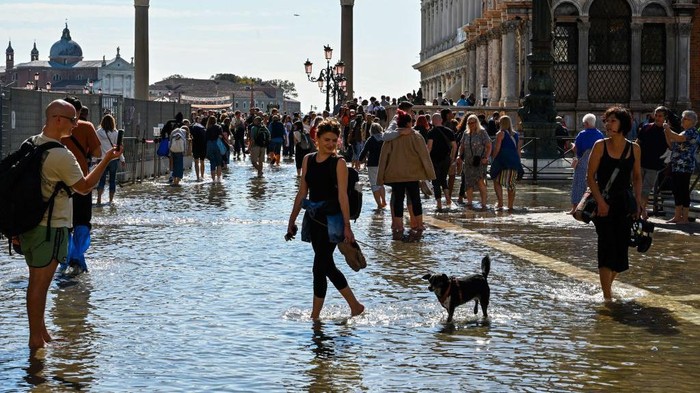 TOPSHOT - Tourists walk across elevated walkways outside St. Mark's Basilica on St. Mark's square in Venice on September 27, 2022, following an 