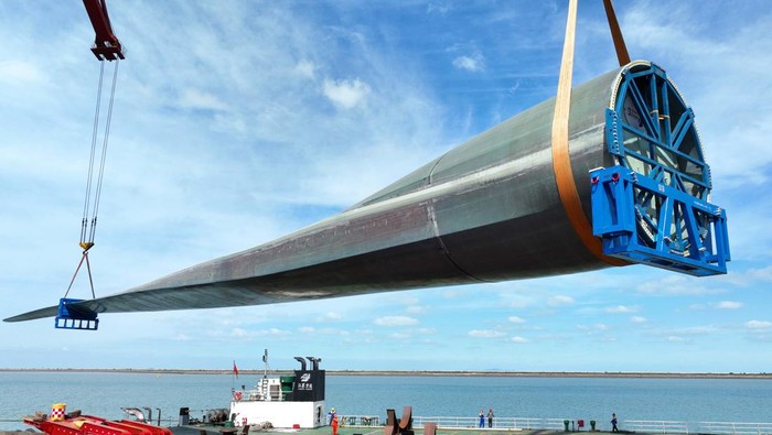 Pernah Lihat Bilah Turbin Angin Terpanjang di Dunia? Nih, Panjang Banget LIANYUNGANG, CHINA - SEPTEMBER 27: A 123-meter-long wind turbine blade is loaded onto a cargo ship at a port on September 27, 2022 in Lianyungang, Jiangsu Province of China. As the world's longest wind turbine blade, it will be transported to Yancheng for trial run. (Photo by VCG/VCG via Getty Images)